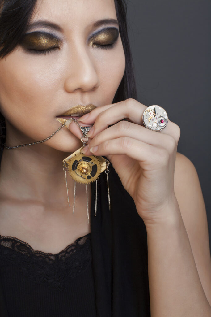 Pendentif steampunk en laiton et bague à mécanisme de montre chromé portés sur un haut noir